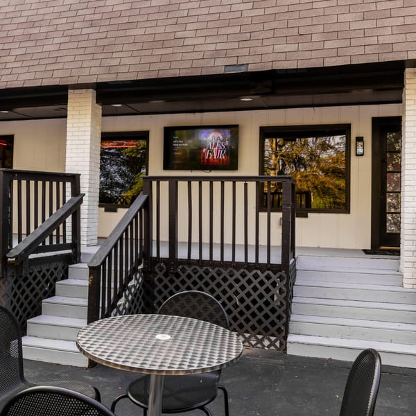 Outdoor patio seating with a metal table and chairs, next to stairs leading to the Frozen Notes entrance.